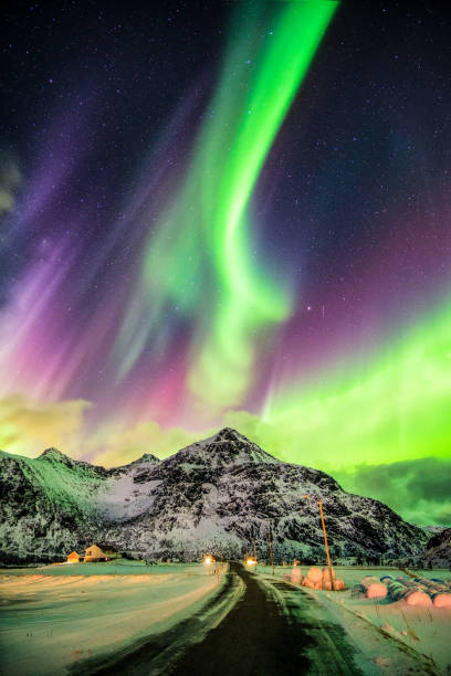 Aurora Borealis (Northern lights) explosion over mountains and rural road at Skagsanden beach, Lofoten island, Norway