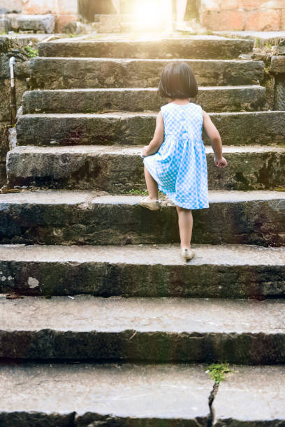 Top view of a schoolgirl in blue uniform descending the stairs in kindergarten school