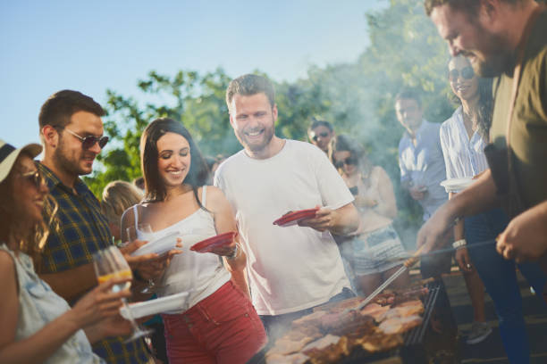 istock Group of people standing around grill. 991856254