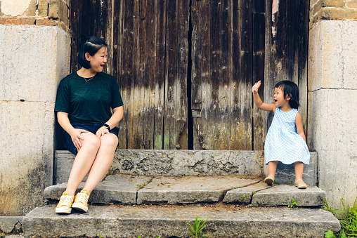 Chinese Daughter and mother sitting on the stairs in the front door.