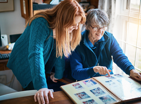 Family history: Granddaughter and grandmother looks through family photo album together.
