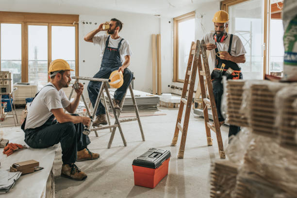 Team of manual workers resting on a coffee break at construction site.