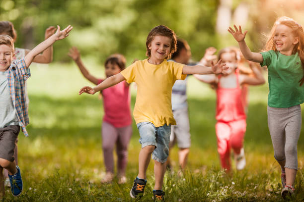 istock Group of happy kids having fun while running in spring day at the park. 991873230