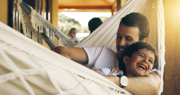 Cropped shot of a father tickling his adorable son on a hammock outside