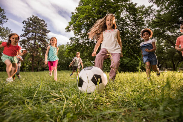 istock Below view of playful children having fun while playing soccer in nature. 991876264