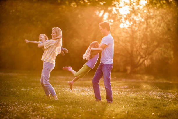 istock Happy family having fun while playing in spring day at sunset. 991878412