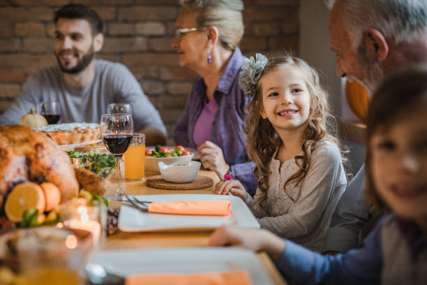 szczęśliwa dziewczyna rozmawia z dziadkiem podczas kolacji przy stole. - dining table child grandparent grandchild zdjęcia i obrazy z banku zdjęć