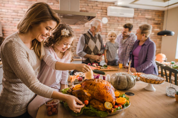 glückliche mutter und tochter bereitet gebratenen truthahn für thanksgiving-dinner. - christmas food dinner turkey stock-fotos und bilder