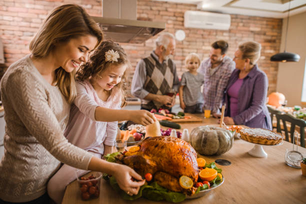 happy mother and daughter preparing roasted turkey for thanksgiving dinner. - christmas turkey imagens e fotografias de stock