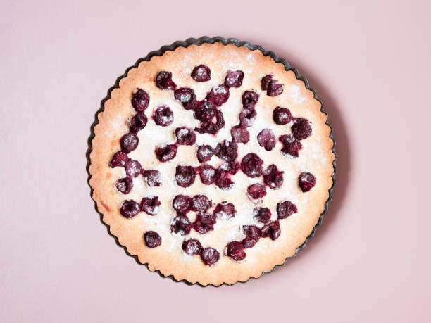 istock Whole homemade cherry cake on pastel pink background. 991886938