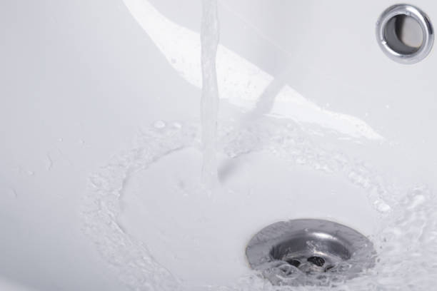 istock hot water flows from the tap, into a white sink 991891438