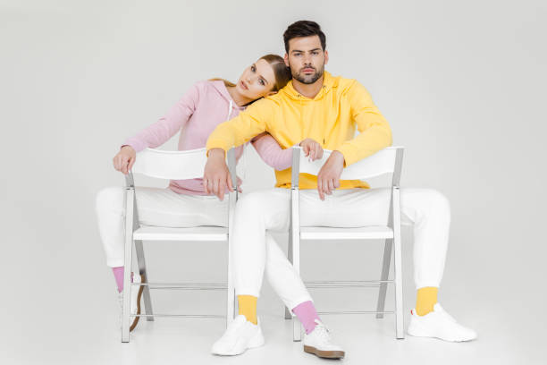 istock couple of models sitting on chairs and looking at camera on white 991892014