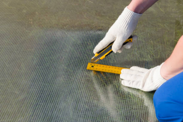 hands of the master in gloves, cut with a knife on the line polycarbonate, for the roof of the greenhouse - unfinish imagens e fotografias de stock