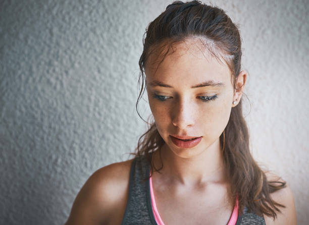istock Beautiful young brunette by wall in sunlight looks down 991892186