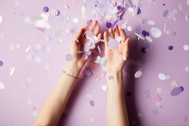 istock cropped image of woman catching falling confetti pieces on surface 991898742