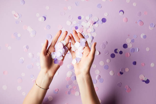 istock cropped image of woman holding falling confetti pieces on surface 991899284