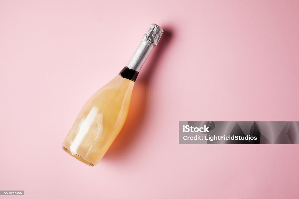 elevated view of bottle of sparkling wine on pink surface Champagne Stock Photo
