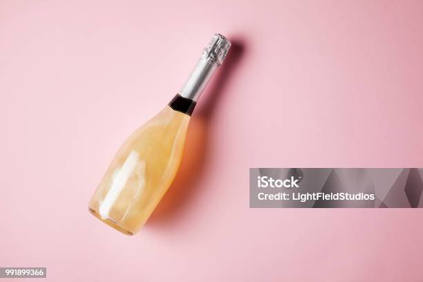 Elevated View Of Bottle Of Sparkling Wine On Pink Surface Stock Photo - Download Image Now