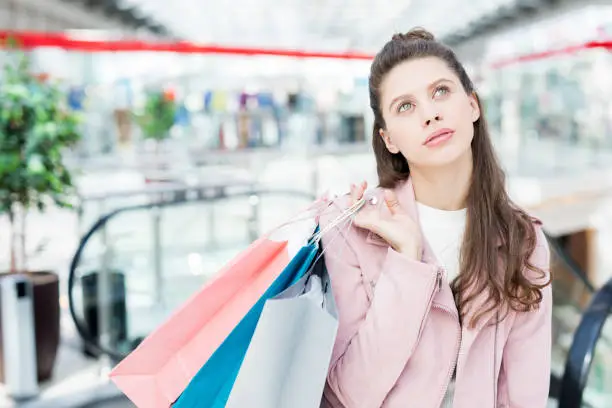 Pensive shopper thinking of what she forgot to buy in the mall on her way back