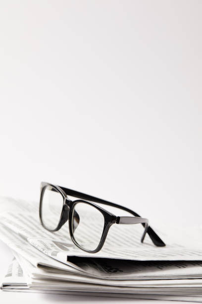 istock close up of newspapers with black eyeglasses, on white with copy space 991904326