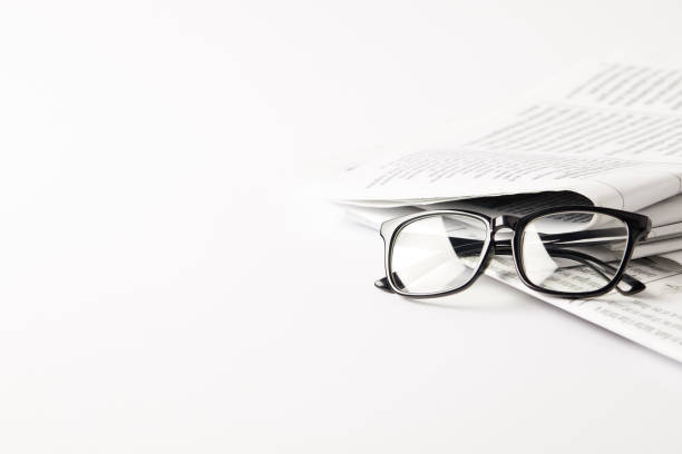 Stack of newspapers in bright setting with reading glasses