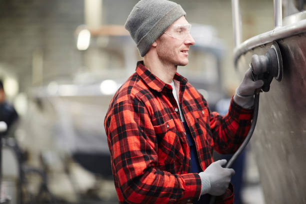 Polishing motorboat Young worker in protective eyeglasses and workwear using polishing machine motorboat maintenance stock pictures, royalty-free photos & images