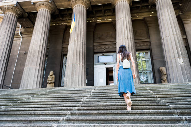 istock back view of woman in denim skirt with backpack walking up steps 991933032