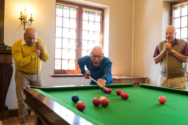 uomo anziano di oltre 90 anni che mostra con sicurezza le sue abilità nello snooker agli amici - pool game pool table aiming men foto e immagini stock