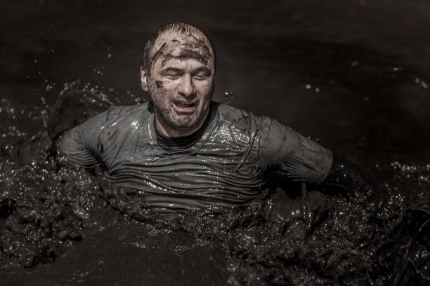 istock Individual man having sporty fun at a public mud run obstacle course 991972166