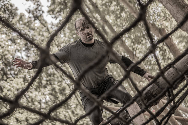 istock Individual man having sporty fun on a rope ladder at a public mud run obstacle course 991973174