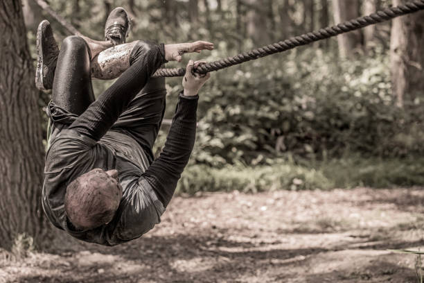 istock Individual man having sporty fun on a rope climb at a public mud run obstacle course 991978118