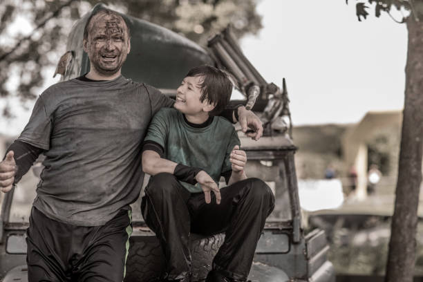 Father and son having sporty fun at a public mud run obstacle course