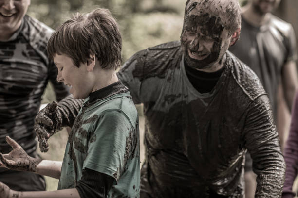 istock Father and son having sporty fun at a public mud run obstacle course 991978640