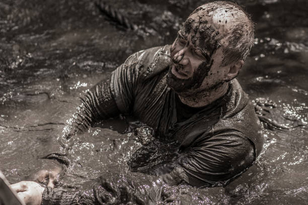 istock Individual man having sporty fun at a public mud run obstacle course 991978946