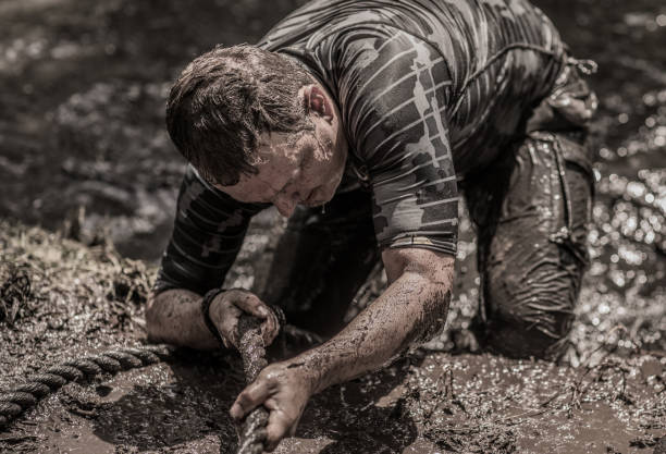 istock Individual man having sporty fun at a public mud run obstacle course 991979216