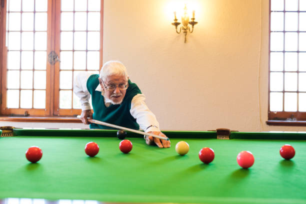 istock Grey haired senior man takes aim with snooker cue 991979616