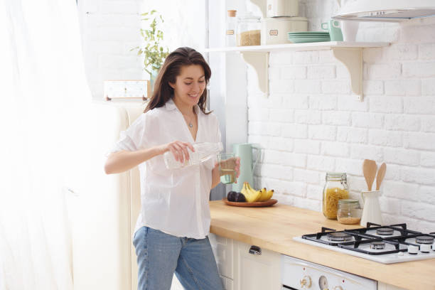istock Young woman drinking water from glass in the kitchen 991983518