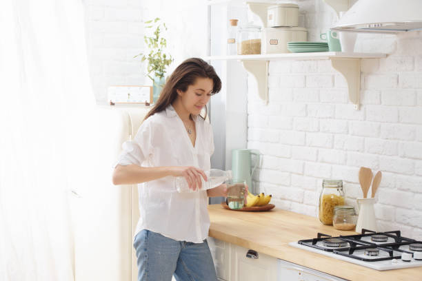 istock Young woman drinking water from glass in the kitchen 991983556