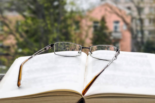 istock Open book and glasses on the open window. 991984124