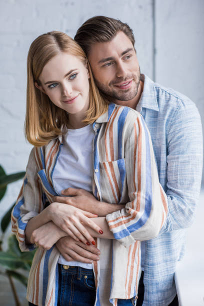 istock young man hugging attractive stylish girlfriend from behind 991992920