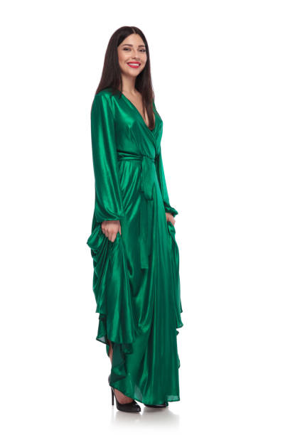 istock smiling brunette girl holding her green gown while standing 991994374