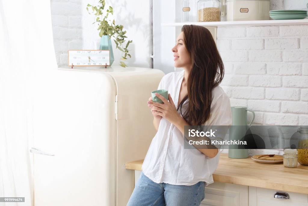 Junge glückliche Frau, die morgens Kaffee in der Küche trinkt. - Lizenzfrei Frauen Stock-Foto