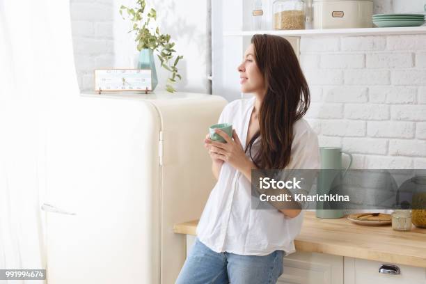 Junge Glückliche Frau Die Morgens Kaffee In Der Küche Trinkt Stockfoto und mehr Bilder von Frauen