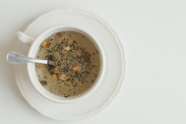 Herbal tea with camomile in white small cup on white table, topn view. Minimal food styling