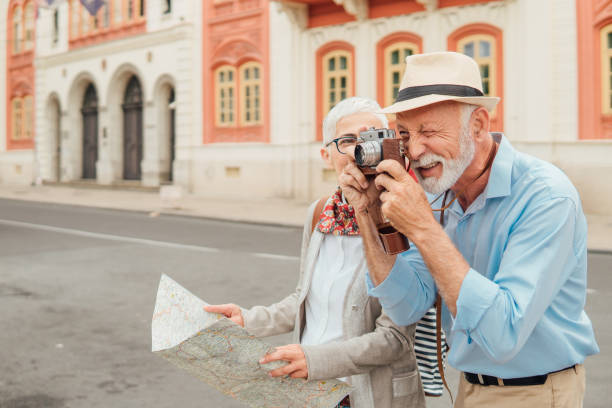 istock Senior woman holding map and looking at her husband using the camera 991998620
