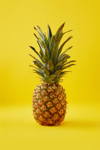 istock close up view of fresh pineapple on yellow background 991998760