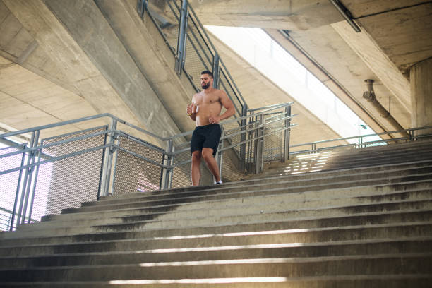 istock Muscular man running outdoors. Stairs climbing 991998858
