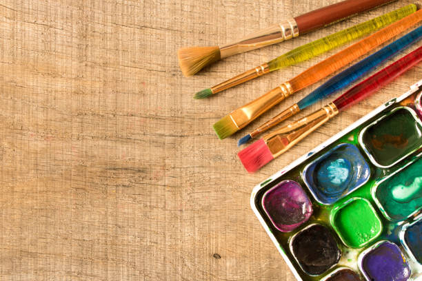 istock Various brushes and paints on the old wooden table . The view from the top. Creative concept 991998912