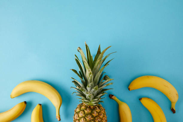 flat lay with fresh bananas and pineapple isolated on blue