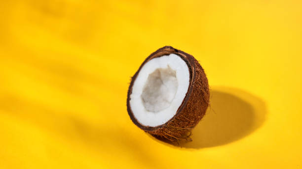 istock Ripe half of coconut on a yellow background. Creative food layout 992002376